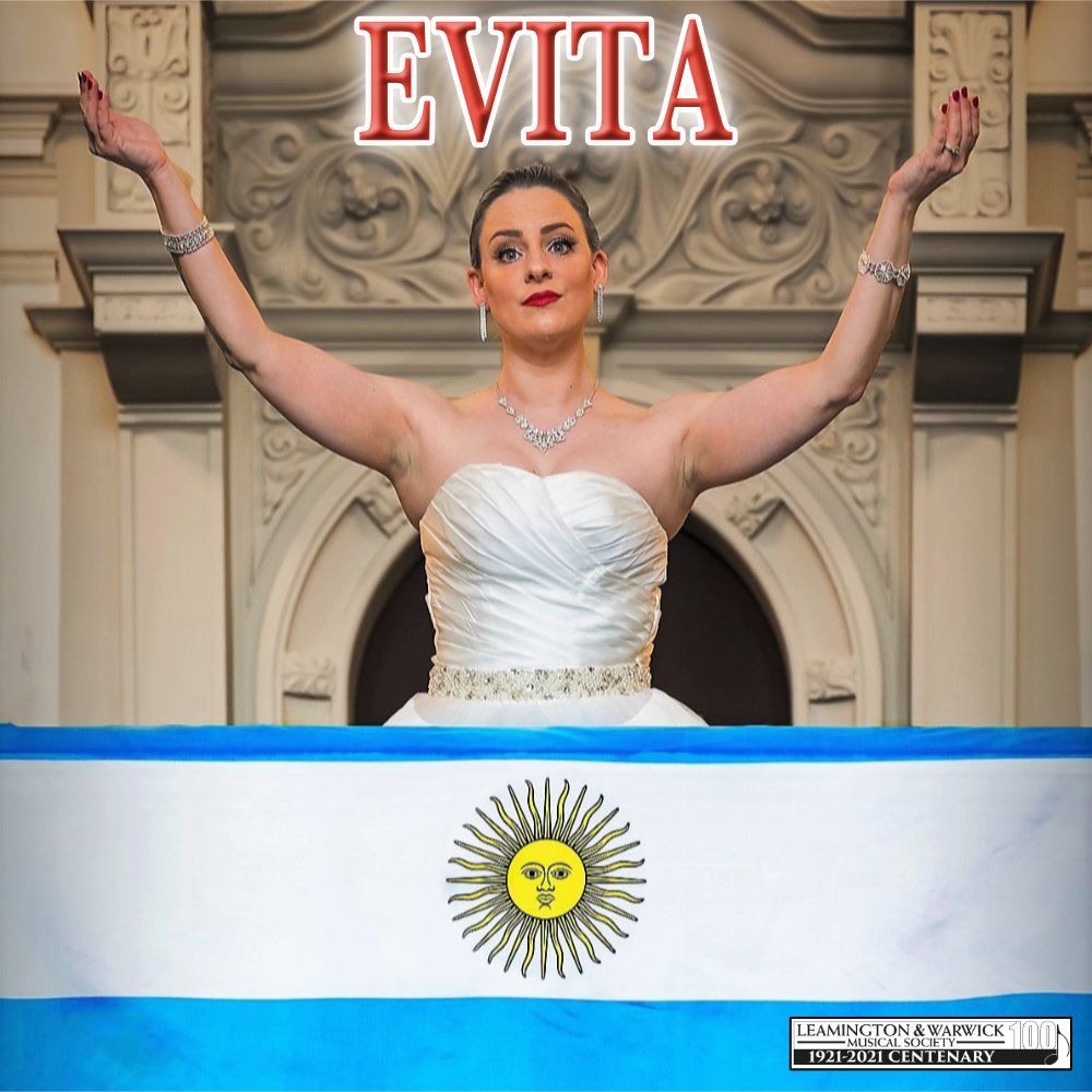 Nelle Cross, as Evita, stands on a balcony with arms raised, with the Argentinian flag in front of her